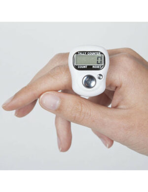 Bague compte-rangs numérique noire avec écran LCD, portée sur un index pour compter les rangs d'un tricot.